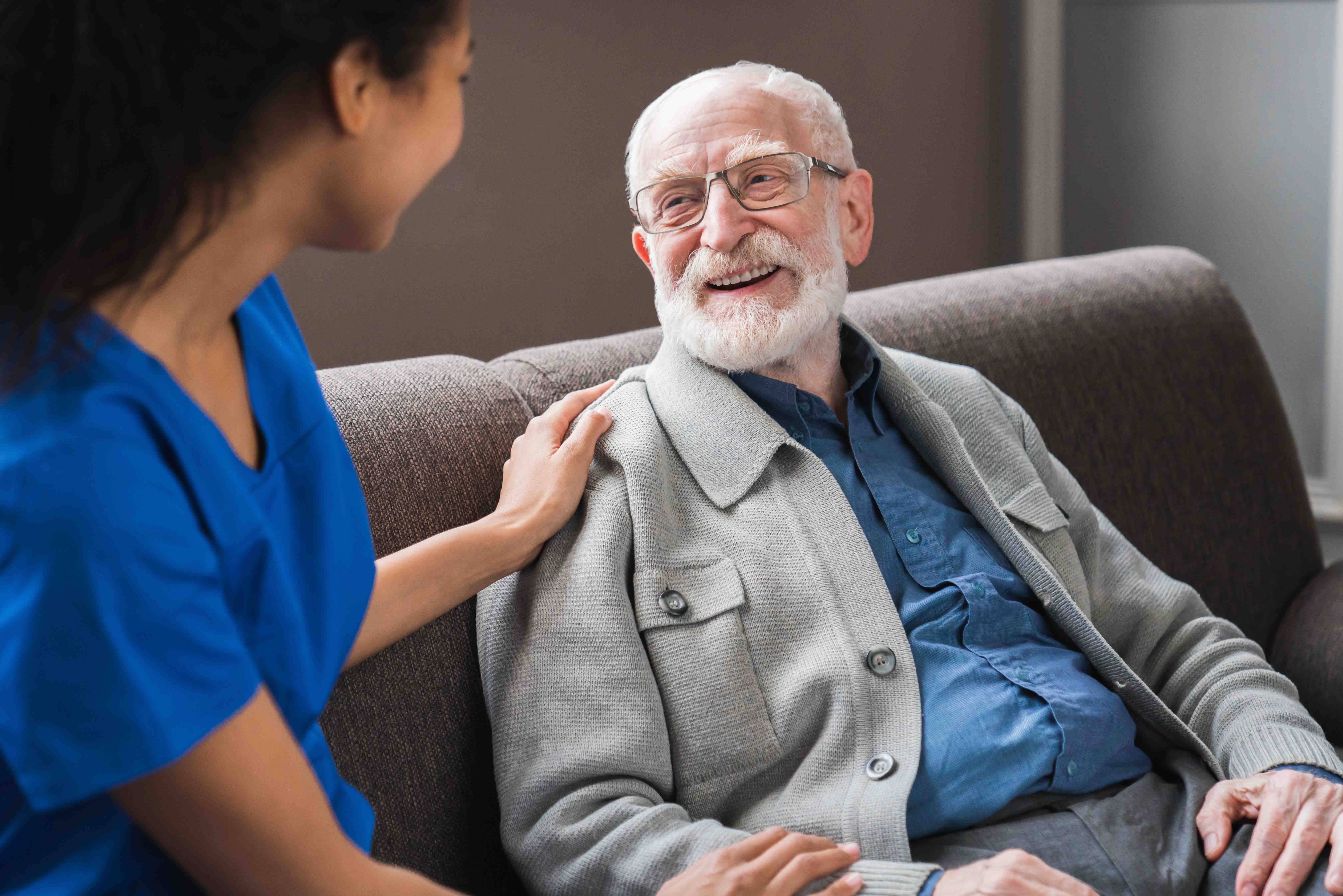 Caregiver having warm conversation with senior patient on couch